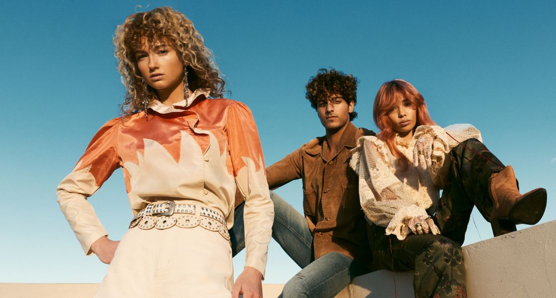 Three people posing against a clear blue sky.