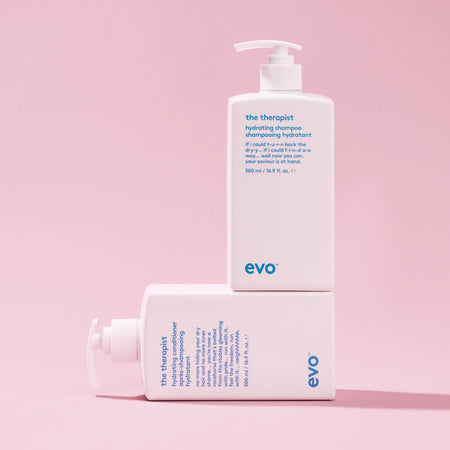 Two bottles of evo 'the therapist' shampoo and conditioner on a pink background