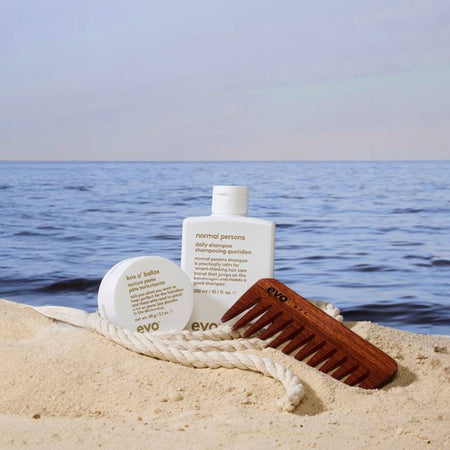 evo hair care products on sand with ocean in the background