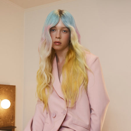 Person with pastel-colored hair wearing a pink jacket indoors.