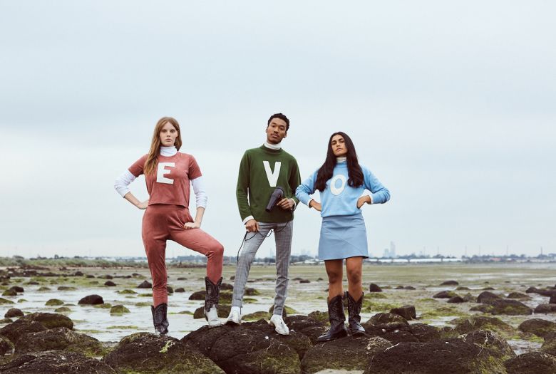 Three people standing on rocks with a plain background