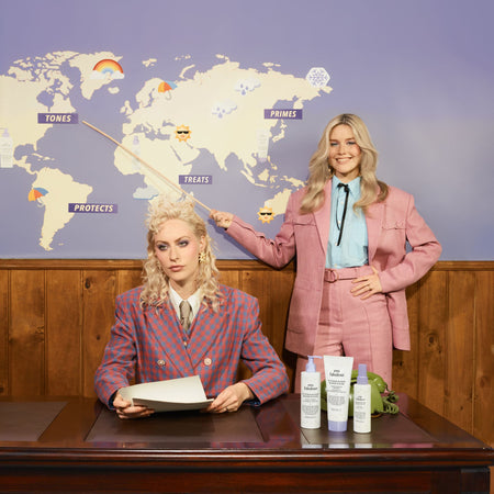 Two women in front of a world map with skincare products on a table.