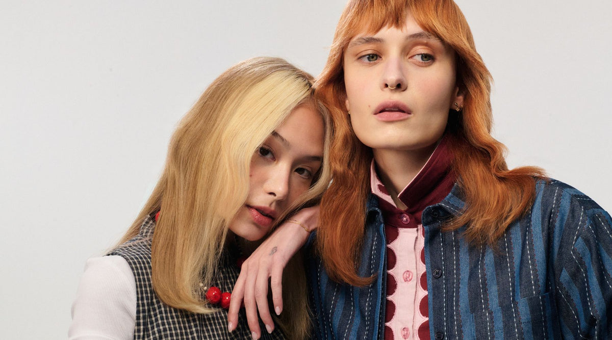 Two women with styled hair posing against a plain background