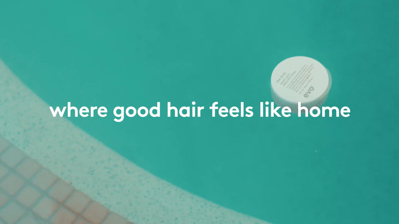 Round white object on a teal surface with text 'where good hair feels like home'.